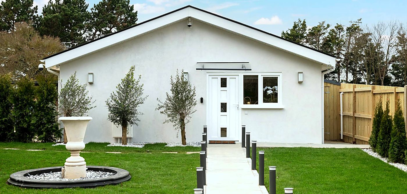 A completed new-build bungalow by Valden Construction with rendered walls, landscaped garden and stone water feature