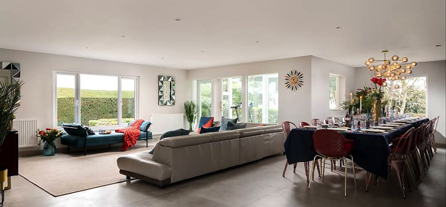 Open-plan living and dining room renovation with large windows and a long banquet table