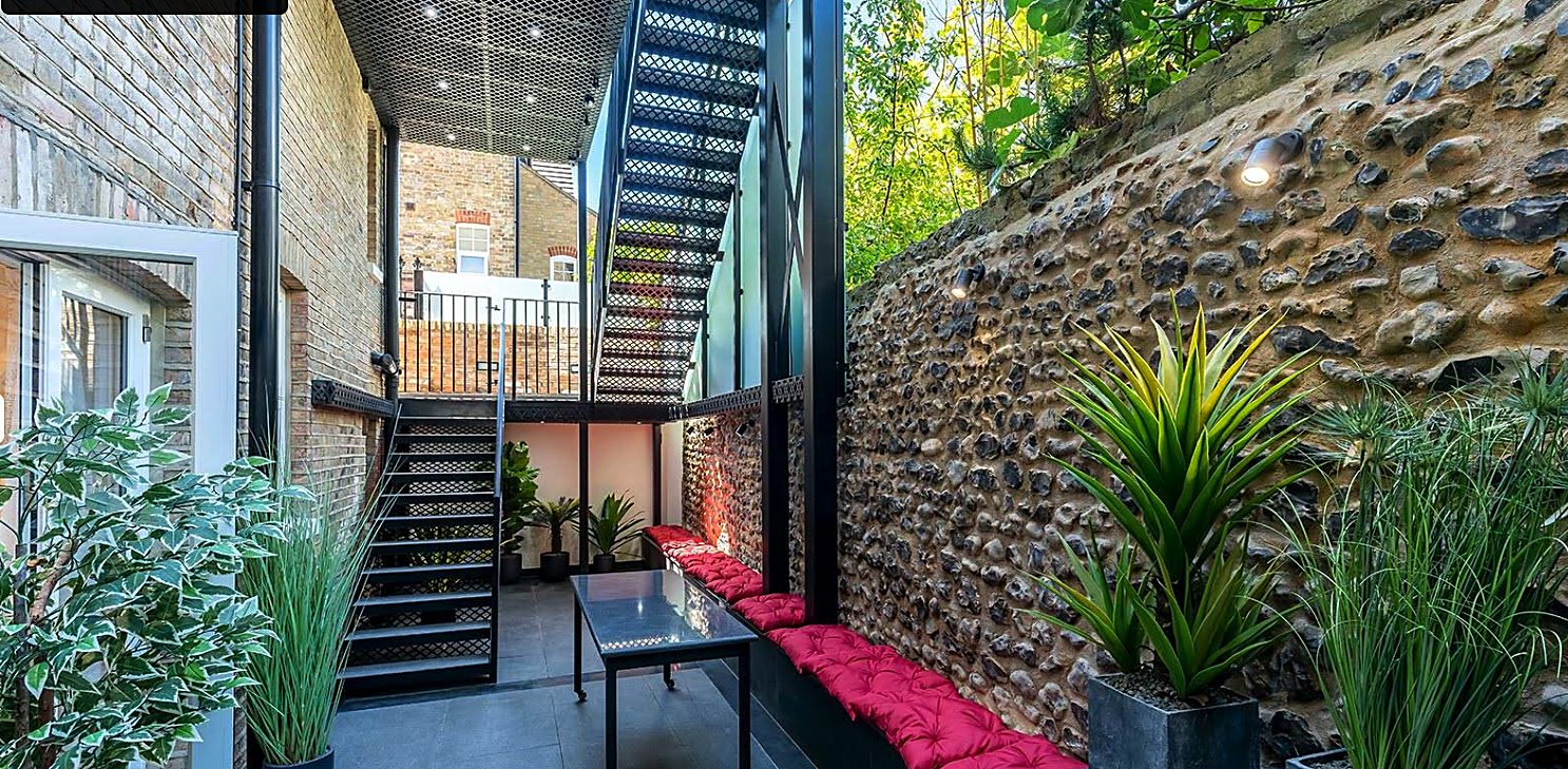 Modern extension courtyard with a feature steel staircase and a flint stone garden wall